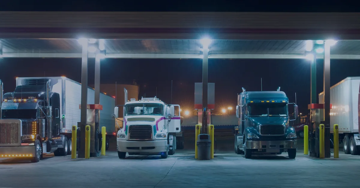 Tractor trailers fueling at night truck stop highlighting differences between tractor fuel vs reefer fuel costs.