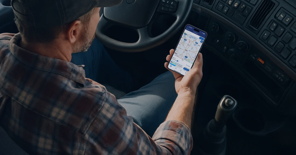 Trucker using smartphone app to find the cheapest diesel fuel prices while sitting in the cab of a truck.
