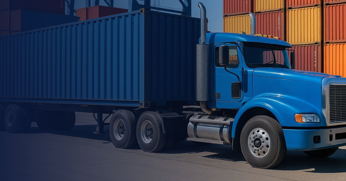 Blue drayage truck hauling a shipping container at the port terminal with colorful stacked containers