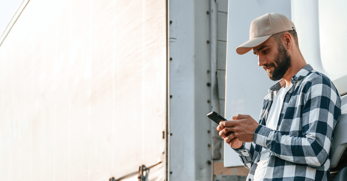 Freight carrier leaning against his semi-truck, looking up the best factoring company.